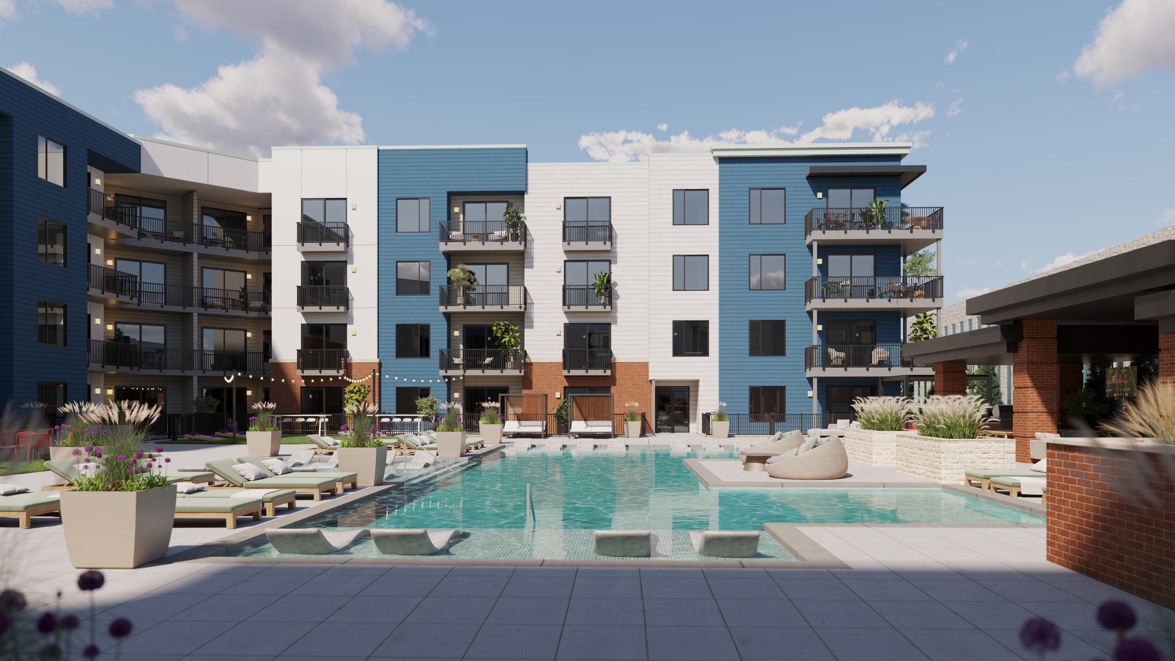 Sonder The pool area at the new apartment complex features lounge chairs, umbrellas, and a clear blue pool surrounded by greenery.