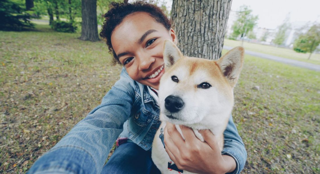 Young couple playing and hugging their pet labrador dog while sitting on the sofa by the window in the living room at home