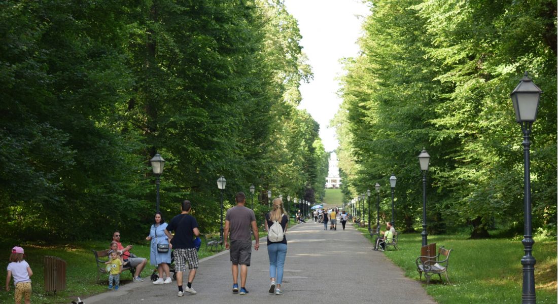 Middle aged woman walking a bike near a park