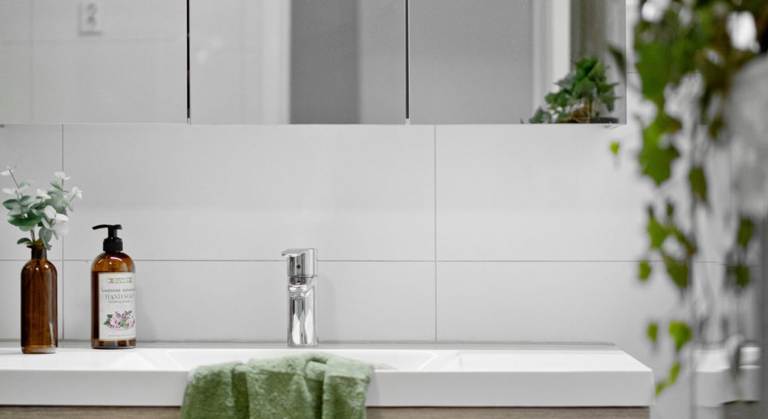 Sonder: A clean bathroom scene with a sink, mirror, and a vibrant green towel displayed prominently.
