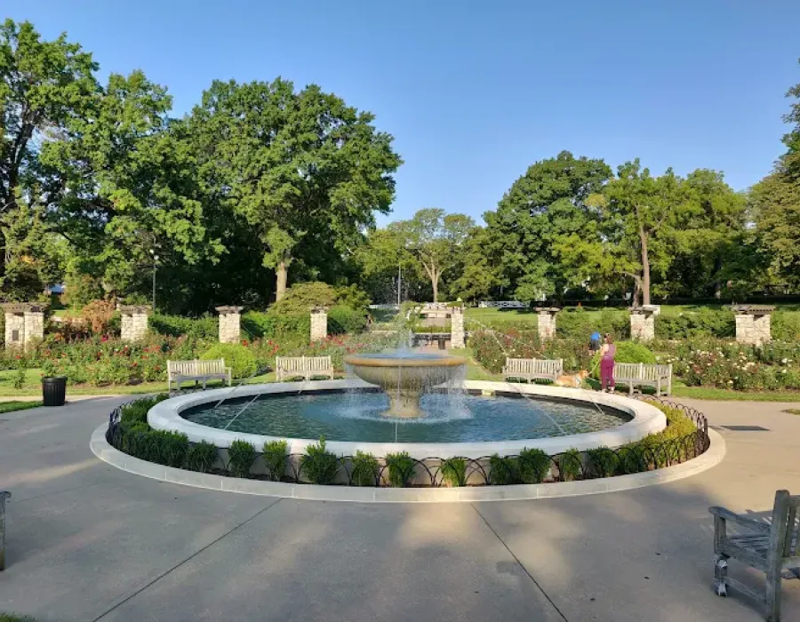 Sonder A park fountain surrounded by benches and trees, creating a serene outdoor space for relaxation.

